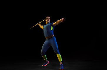 Image showing Male athlete practicing in throwing javelin isolated on black studio background in neon light