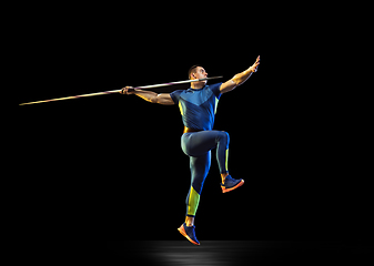 Image showing Male athlete practicing in throwing javelin isolated on black studio background in neon light