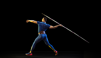 Image showing Male athlete practicing in throwing javelin isolated on black studio background in neon light