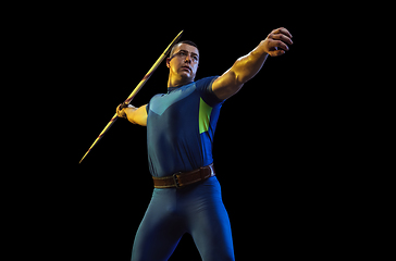 Image showing Male athlete practicing in throwing javelin isolated on black studio background in neon light