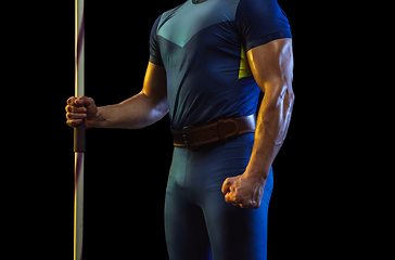 Image showing Male athlete practicing in throwing javelin isolated on black studio background in neon light