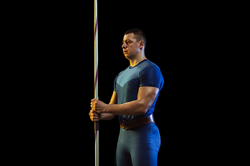 Image showing Male athlete practicing in throwing javelin isolated on black studio background in neon light