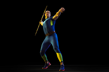 Image showing Male athlete practicing in throwing javelin isolated on black studio background in neon light