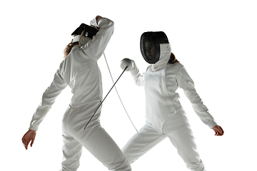 Image showing Teen girls in fencing costumes with swords in hands isolated on white background