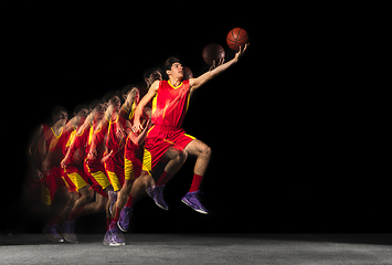 Image showing Young caucasian basketball player in motion and action in mixed light on dark background. Concept of healthy lifestyle, professional sport, hobby.