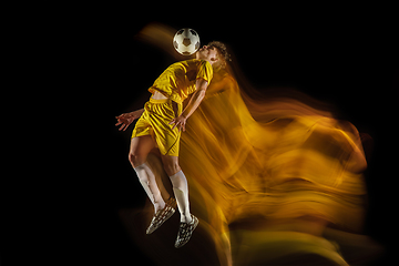 Image showing Young caucasian male football or soccer player kicking ball for the goal in mixed light on dark background. Concept of healthy lifestyle, professional sport, hobby.