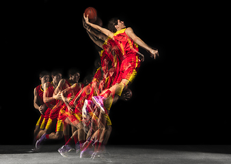 Image showing Young caucasian basketball player in motion and action in mixed light on dark background. Concept of healthy lifestyle, professional sport, hobby.