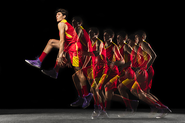 Image showing Young caucasian basketball player in motion and action in mixed light on dark background. Concept of healthy lifestyle, professional sport, hobby.