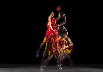 Image showing Young caucasian basketball player in motion and action in mixed light on dark background. Concept of healthy lifestyle, professional sport, hobby.