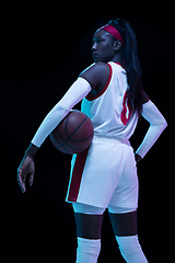 Image showing Beautiful african-american female basketball player in motion and action in neon light on black background. Concept of healthy lifestyle, professional sport, hobby.