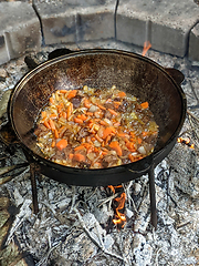 Image showing gourmet beef stew cooked in cauldron on outdoor fire pit