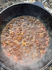 Image showing gourmet beef stew cooked in cauldron on outdoor fire pit