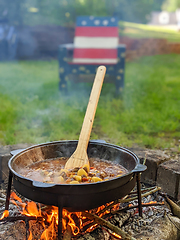 Image showing gourmet beef stew cooked in cauldron on outdoor fire pit