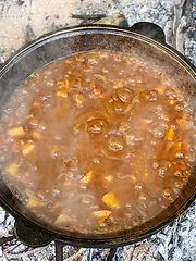 Image showing gourmet beef stew cooked in cauldron on outdoor fire pit