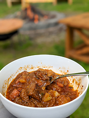 Image showing gourmet beef stew cooked in cauldron on outdoor fire pit