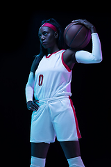 Image showing Beautiful african-american female basketball player in motion and action in neon light on black background. Concept of healthy lifestyle, professional sport, hobby.