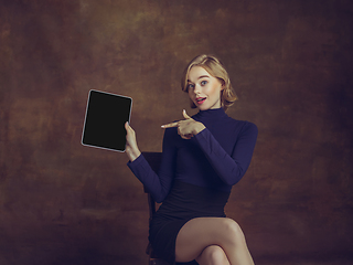 Image showing Young woman in art action isolated on brown background. Retro style, comparison of eras concept.