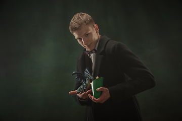 Image showing Young man in art action isolated on dark green background. Retro style, comparison of eras concept.