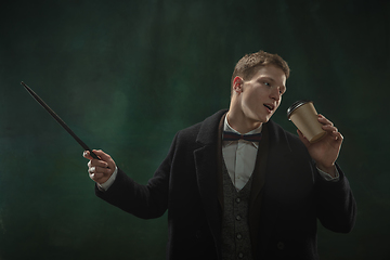 Image showing Young man in art action isolated on dark green background. Retro style, comparison of eras concept.