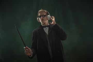 Image showing Young man in art action isolated on dark green background. Retro style, comparison of eras concept.