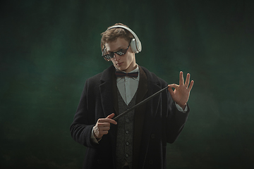 Image showing Young man in art action isolated on dark green background. Retro style, comparison of eras concept.