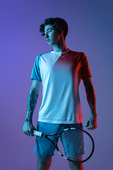 Image showing Young caucasian man playing tennis isolated on purple-blue studio background in neon, action and motion concept