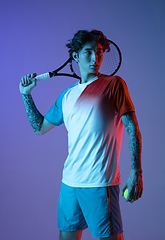 Image showing Young caucasian man playing tennis isolated on purple-blue studio background in neon, action and motion concept