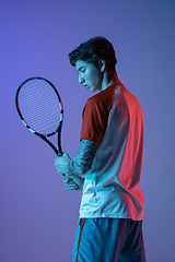 Image showing Young caucasian man playing tennis isolated on purple-blue studio background in neon, action and motion concept