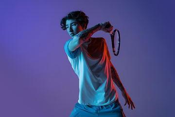 Image showing Young caucasian man playing tennis isolated on purple-blue studio background in neon, action and motion concept