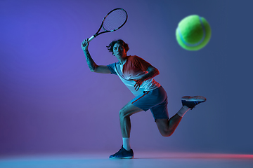 Image showing Young caucasian man playing tennis isolated on purple-blue studio background in neon, action and motion concept