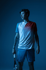 Image showing Young caucasian man playing tennis isolated on blue studio background in neon, action and motion concept