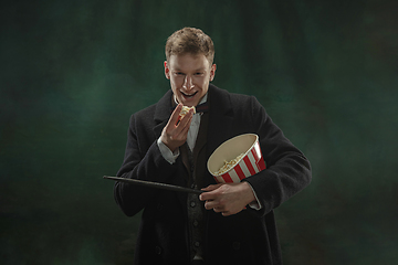 Image showing Young man in art action isolated on dark green background. Retro style, comparison of eras concept.