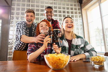 Image showing Group of friends watching sport match together. Emotional fans cheering for favourite team, watching on exciting game. Concept of friendship, leisure activity, emotions