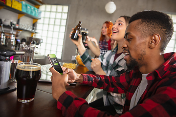 Image showing Group of friends watching sport match together. Emotional fans cheering for favourite team, watching on exciting game. Concept of friendship, leisure activity, emotions