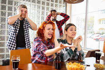 Image showing Group of friends watching sport match together. Emotional fans cheering for favourite team, watching on exciting game. Concept of friendship, leisure activity, emotions