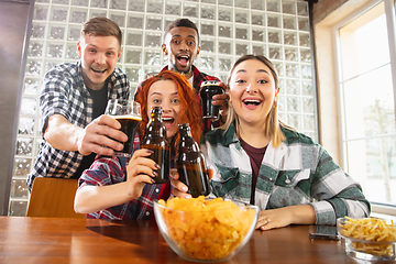 Image showing Group of friends watching sport match together. Emotional fans cheering for favourite team, watching on exciting game. Concept of friendship, leisure activity, emotions