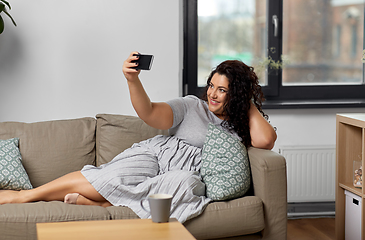 Image showing happy woman taking selfie with smartphone at home