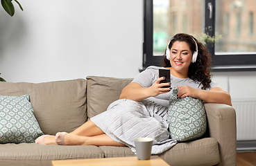 Image showing woman in headphones listens to music on smartphone