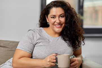 Image showing happy woman drinking coffee or tea on sofa at home