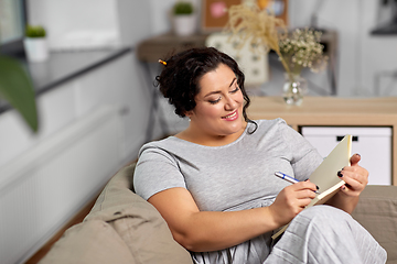 Image showing happy young woman with diary on sofa at home