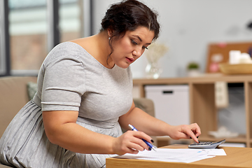 Image showing woman with papers and calculator working at home