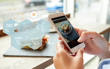 Image showing hands with phone and food nutritional value chart