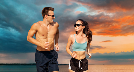 Image showing couple in sports clothes running along on beach