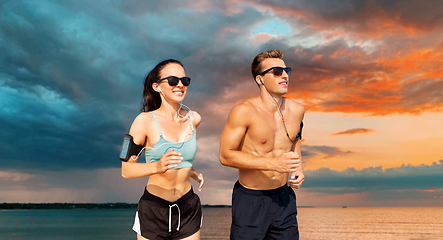 Image showing couple with phones and arm bands running over sea