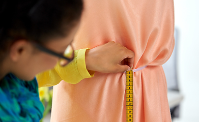 Image showing fashion designer measuring dress with tape measure