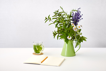 Image showing herbal tea, notebook and flowers in jug on table