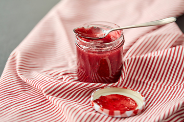 Image showing mason jar with raspberry jam and spoon on towel