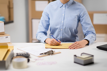 Image showing woman writing on parcel envelope at post office