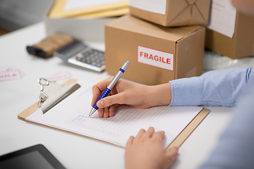 Image showing hands with clipboard and parcels at post office