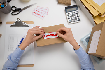 Image showing woman sticking fragile mark to parcel box